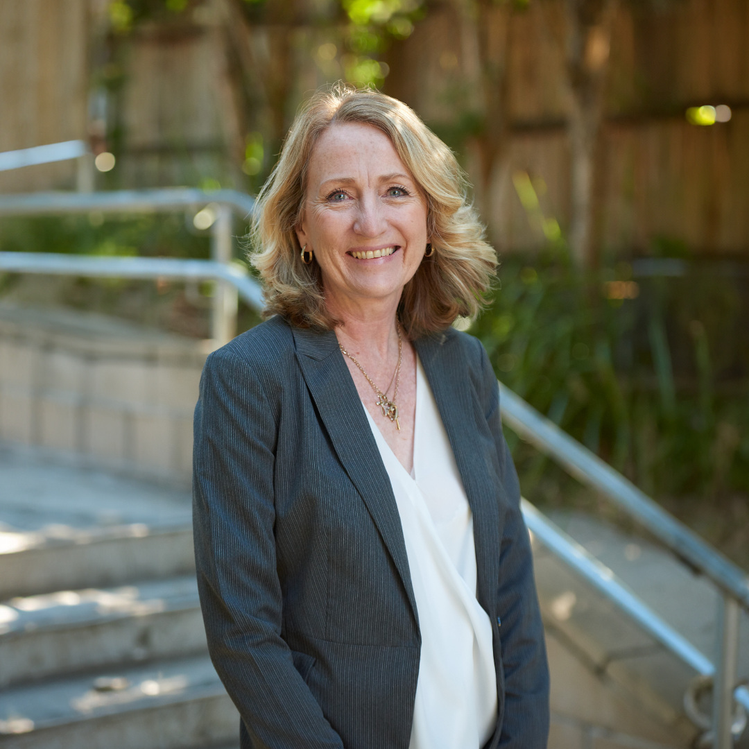 School principal standing on school grounds, representing leadership, approachability and connection with the school community